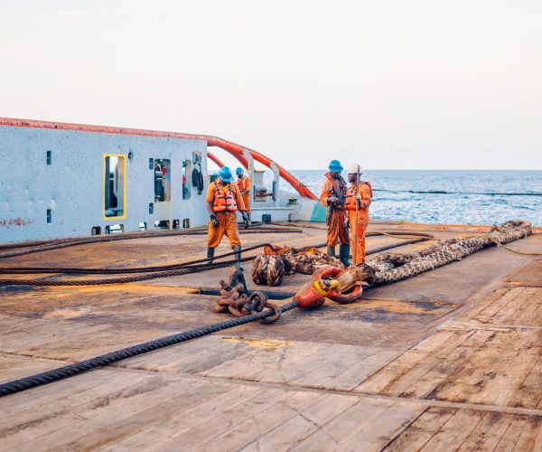 Anchor-handling Tug Supply AHTS vessel crew preparing vessel for static tow tanker lifting. Ocean tug job. AB and Bosun on deck. They pull towing wire